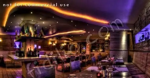 نمایی از فضای داخلی رستوران دارچین با طراحی مدرن و دلنشین، نورپردازی خاص و دکوراسیون گرم، شامل میز و صندلی‌ها و بار نوشیدنی.