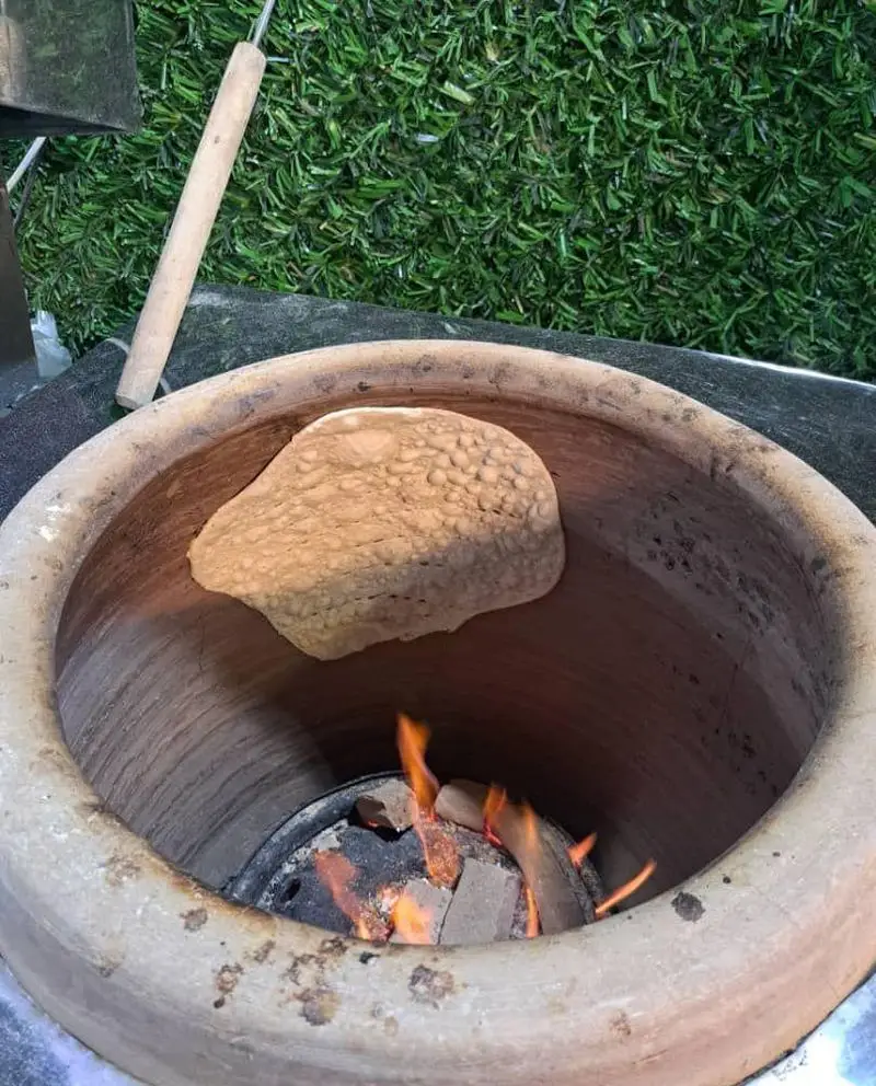 نمایی از پخت نان داغ سنتی و تازه در تنور سفالی مخصوص جگر سرای دل تو، آماده سرو در کنار لذیذترین جگرها.