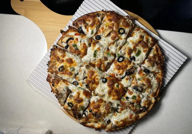 پیتزای داغ و لذیذ مستر پیتزا با پنیر ذوب شده طلایی، زیتون سیاه، فلفل دلمه ای و قارچ، ایده‌آل برای سفارش و تجربه طعمی به‌یادماندنی.