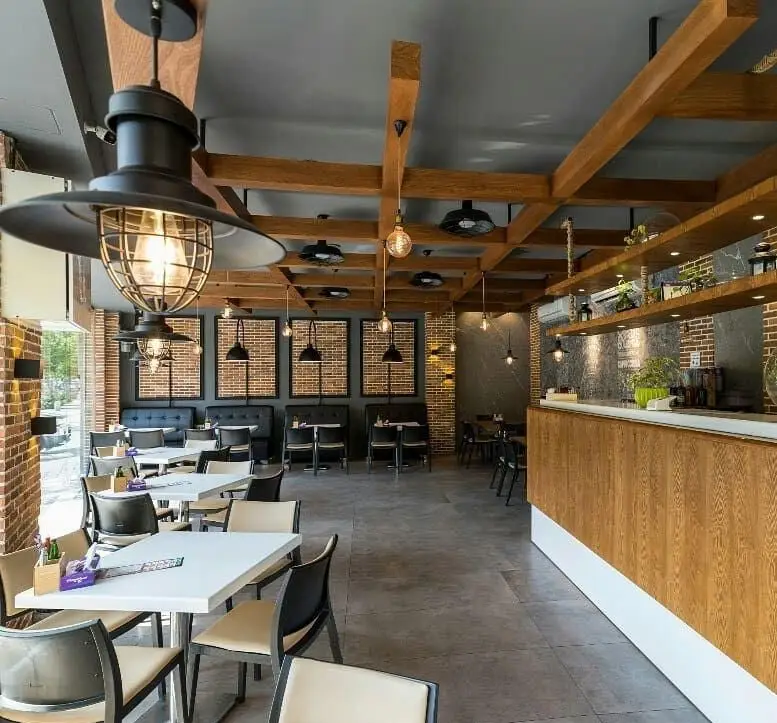 فضای داخلی مدرن و دنج پیتزا سیب ۳۶۰ شعبه پیروزی با دکوراسیون شیک، شامل میز و صندلی، کانتر چوبی و نورپردازی صنعتی