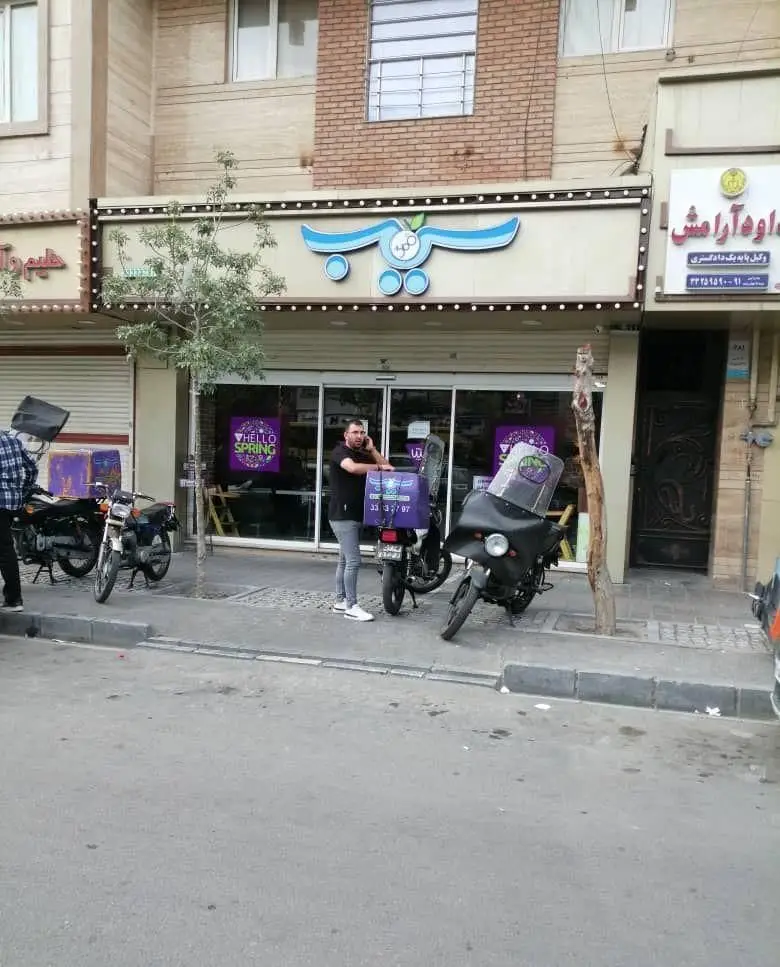 تصویر نمای بیرونی پیتزا سیب ۳۶۰ شعبه پیروزی با لوگوی متمایز و موتورسیکلت‌های دلیوری آماده ارسال سفارشات مشتریان.