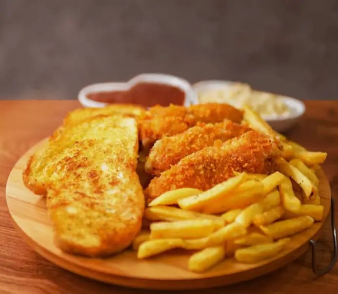 سینی غذای خوشمزه چاکوچ شامل فیله سوخاری، سیب زمینی سرخ کرده و نان سیر با سس‌های متنوع برای تجربه طعمی دلپذیر در رستوران.