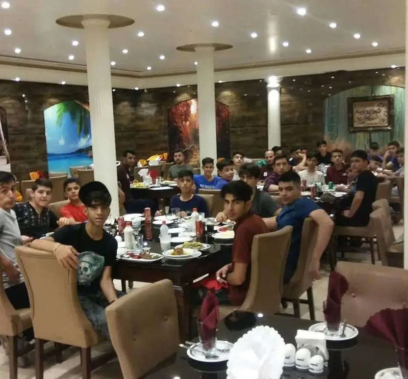 جوانان و نوجوانان در حال صرف وعده غذایی در محیطی دوستانه و جذاب در رستوران آرامیس. یک دورهمی به یادماندنی.