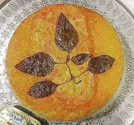 ته دیگ طلایی و خوش‌طعم باغ رستوران سنتی گل یخ، مزین به طرح برگ. لذت غذای اصیل و سنتی ایرانی.