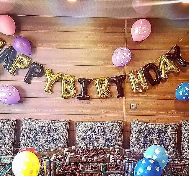 جشن تولد به یادماندنی در باغ رستوران سنتی گل یخ با بادکنک آرایی شاد، بنر تولد و چیدمان سنتی دلنشین با کوسن‌های طرح‌دار.