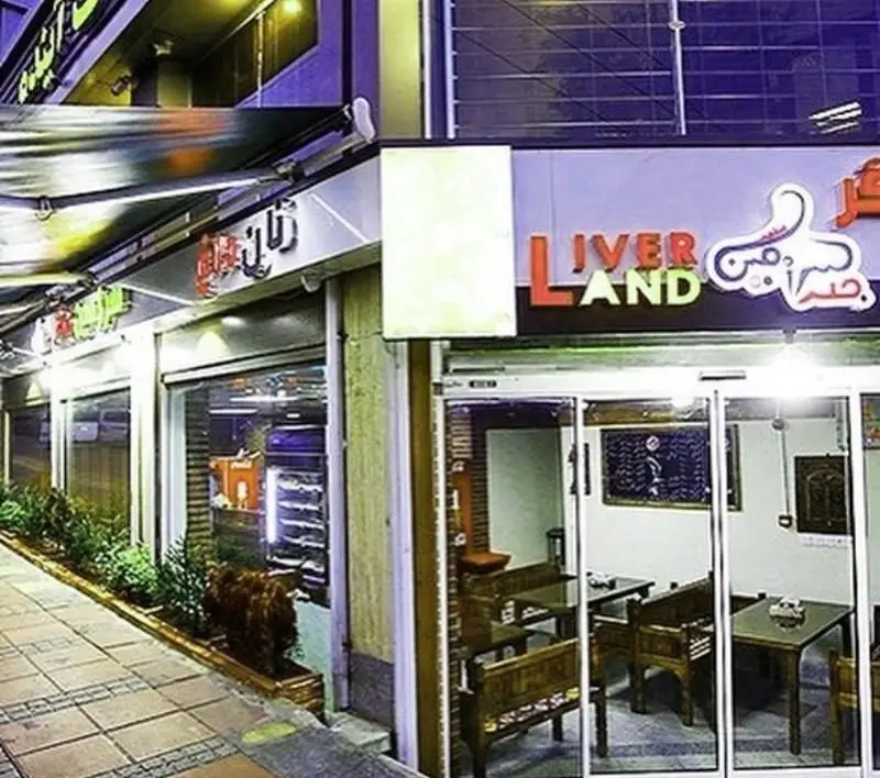 نمای بیرونی روشن کبابی و جگرکی سرزمین جگر (Liver Land) با تابلوی رنگی، ورودی شیشه‌ای، فضای داخلی با مبلمان چوبی و گلدان‌های تزئینی.