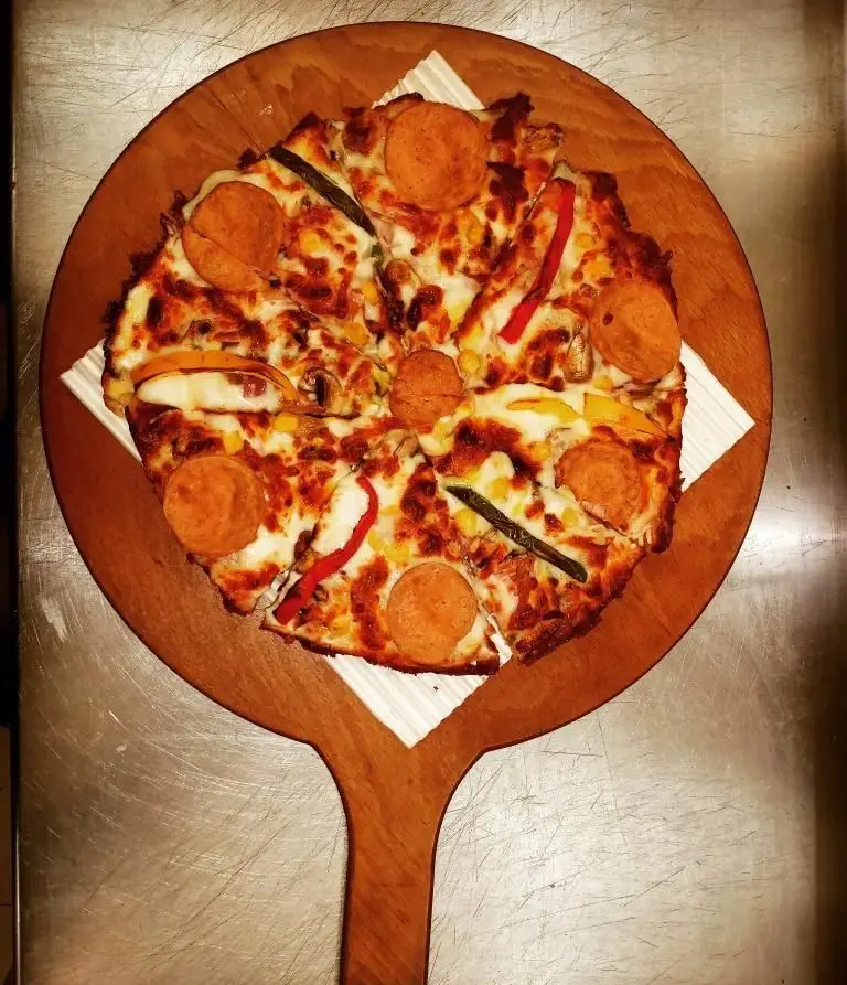 پیتزای پپرونی و سبزیجات متنوع (فلفل دلمه‌ای، ذرت، قارچ) با پنیر آب‌شده طلایی از وینر برگر، سرو شده روی سینی چوبی مخصوص.