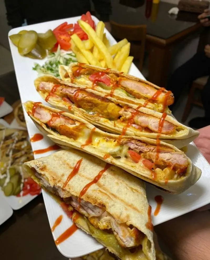 طعم بی‌نظیر ساندویچ‌های رپ مرغ گریل شده وینر برگر، همراه با سیب‌زمینی سرخ کرده، خیارشور و گوجه. انتخابی عالی برای فست فود.