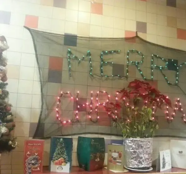 تزیینات کریسمس و سال نو در پیتزا سورن با چراغ‌های روشن، درخت کاج، و کارت پستال‌های تبریک. فضای شاد و جشن در رستوران.