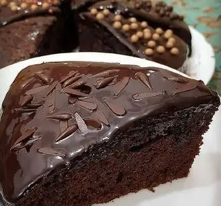 برشی از کیک شکلاتی خیس و لذیذ با روکش گاناش براق و تزئینات شکلاتی، از محصولات پرطرفدار قنادی اصل تبریز برای جشن‌ها.