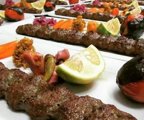 لذت چشیدن کباب کوبیده تازه و آبدار کبابی علیرضا رضایی، سرو شده با مخلفات اصیل ایرانی مانند لیمو، ترشی و گوجه کبابی.