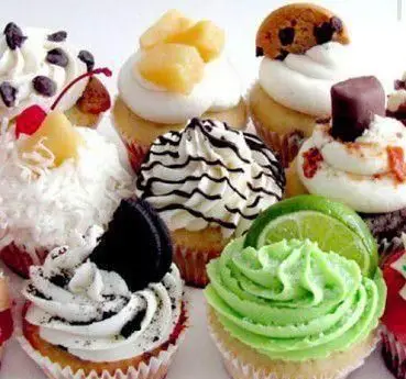 تصویری از کاپ کیک‌های متنوع و رنگارنگ با تزئینات دلپذیر شکلات، میوه و خامه، شیرینی‌های محبوب قنادی فرشته شیرین.