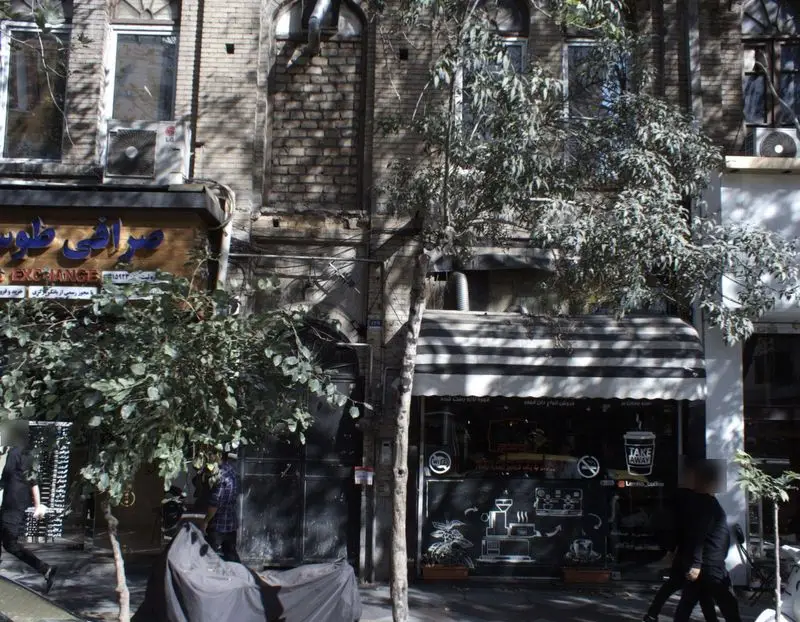 نمای بیرونی دن کافه شعبه فردوسی در تهران، با سایبان راه راه مشکی و سفید و نقاشی‌های دیواری مرتبط با قهوه.