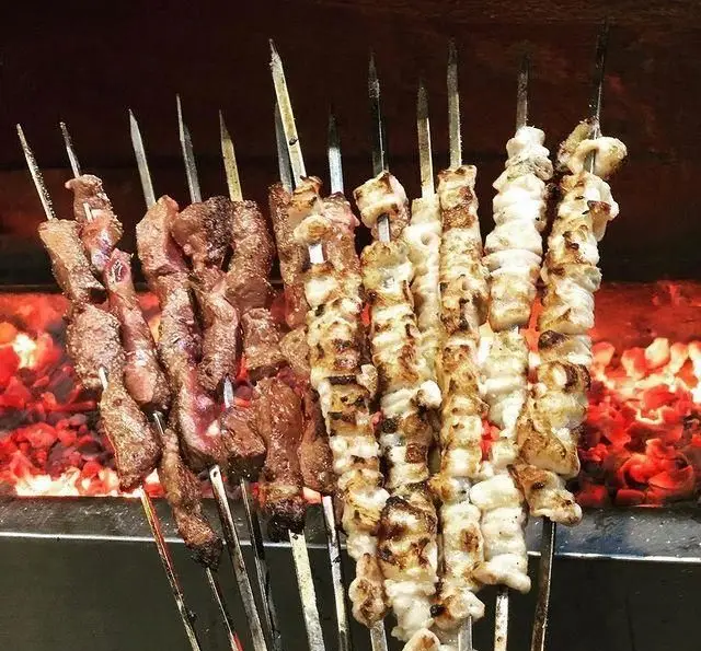 کباب‌های جگر و جوجه تازه بر روی ذغال گداخته در جگرکی بابا شمل؛ تجربه‌ای لذیذ از کباب‌های سنتی ایرانی و غذای خیابانی.