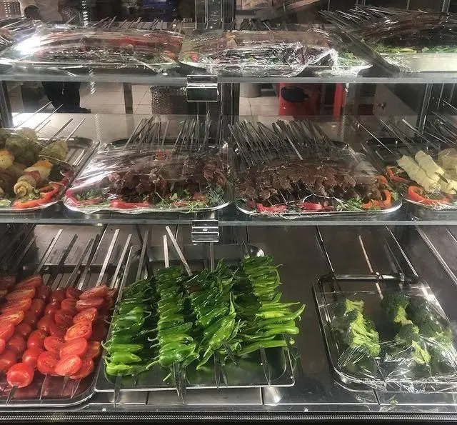 ویترین جذاب جگرکی بابا شمل با انواع سیخ‌های کباب، جگر، دل، قلوه و سبزیجات تازه شامل گوجه، فلفل و بروکلی، آماده طبخ.
