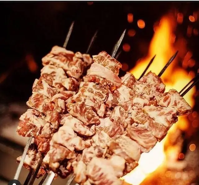 سیخ‌های گوشت تازه و باکیفیت جگرکی بابا شمل در حال آماده‌سازی برای کباب شدن روی آتش، بهترین کباب و جگر تهران