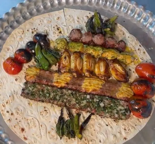 سینی بزرگ کباب های لذیذ جگرکی بابا شمل شامل انواع جگر، بال مرغ، کباب کوبیده سبزیجات، گوجه و فلفل کبابی روی نان تازه سنتی
