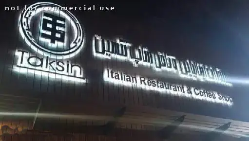 تصویری از تابلوی سردر روشن رستوران و کافی شاپ ایتالیایی تکسین در شب، نشان‌دهنده برند و خدمات این کسب و کار محبوب.