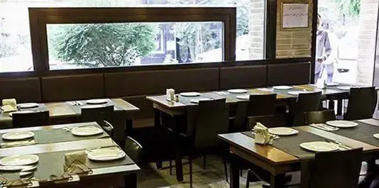 نمای داخلی رستوران تکسین، میزهای چیده شده آماده پذیرایی از مشتریان در فضایی آرام و دلپذیر.