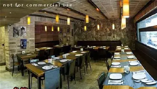 نمایی از دکوراسیون داخلی رستوران تکسین با دیوارهای سنگی و آجری، نورپردازی گرم و میزهای آماده پذیرایی از مهمانان در فضایی دنج.