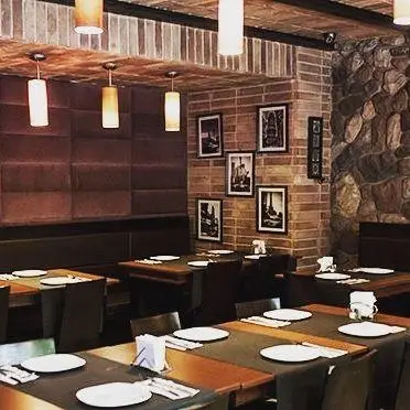 فضای داخلی لوکس و مدرن رستوران تکسین، با دکوراسیون سنگی و چوبی، میزهای مرتب و نورپردازی دلپذیر برای مشتریان.