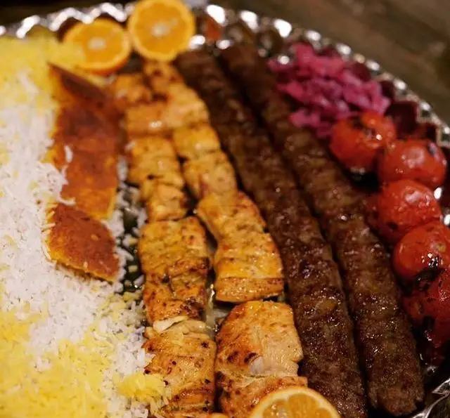 سینی چلوکباب‌های لذیذ ایرانی: کوبیده و جوجه به همراه برنج زعفرانی، ته دیگ و گوجه کبابی؛ بهترین غذای سنتی در رستوران مجلل شهرری.