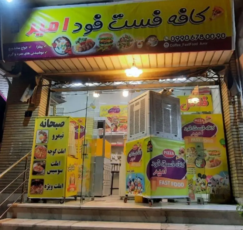 نمای بیرونی کافه فست فود امیر با تابلوی روشن، ارائه دهنده پیتزا، انواع ساندویچ، صبحانه و نوشیدنی های سرد و گرم. تماس: 09906780090