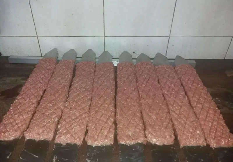 کباب کوبیده گوشت تازه آماده طبخ بر روی سیخ‌های مخصوص، با نقش‌ونگاری زیبا، در محیط بهداشتی رستوران نارنج.