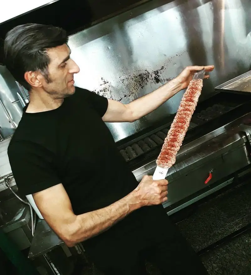 آشپز ماهر رستوران نارنج مشغول آماده‌سازی کباب کوبیده اصیل ایرانی با گوشت تازه در آشپزخانه حرفه‌ای.