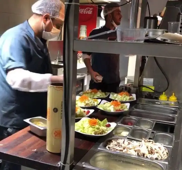 آشپزهای کافه رستوران دورهمی امامزاده حسن در حال آماده‌سازی و سرو سالادهای تازه و بهداشتی برای مشتریان در آشپزخانه.