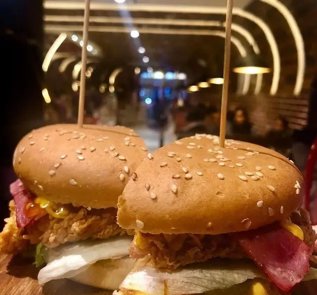 تصویری از دو برگر ویژه مرغ سوخاری با کیفیت عالی در کافه رستوران دورهمی امامزاده حسن، ایده‌آل برای یک وعده غذایی لذیذ و به یادماندنی.