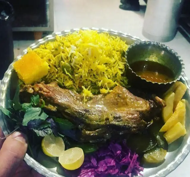 یک بشقاب غذای کامل و لذیذ کافه رستوران دورهمی امامزاده حسن شامل گوشت، پلو زعفرانی، دورچین متنوع و سس.