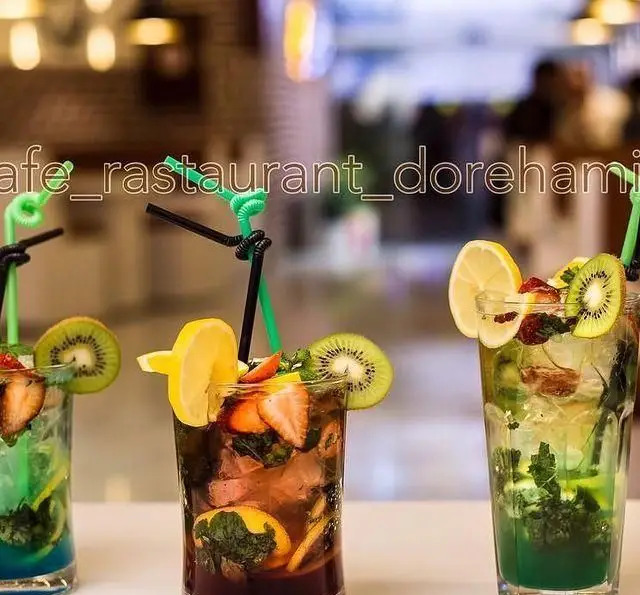 تصویری از نوشیدنی‌های خنک و رنگارنگ، شامل موهیتو با میوه‌های تازه کیوی، لیمو و توت‌فرنگی در کافه رستوران دورهمی امامزاده حسن.