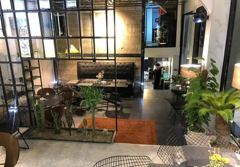 فضای داخلی کافه رستوران عمو سهراب؛ دکوراسیون مدرن و صنعتی با دیوارهای آجری، مبلمان شیک، گیاهان سبز، نورپردازی گرم و محیطی دلنشین برای مشتریان.