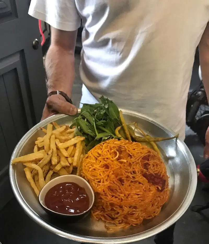 بشقاب غذای کافه رستوران عمو سهراب شامل اسپاگتی با سس مخصوص، سیب زمینی سرخ کرده، سالاد سبز تازه و ترشی فلفل به همراه سس کچاپ.