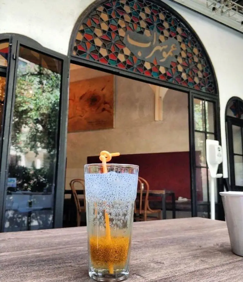 فضای دلنشین و نوشیدنی‌های متنوع در کافه رستوران عمو سهراب، با نمای ورودی سنتی و پنجره‌های رنگی چشم‌نواز.