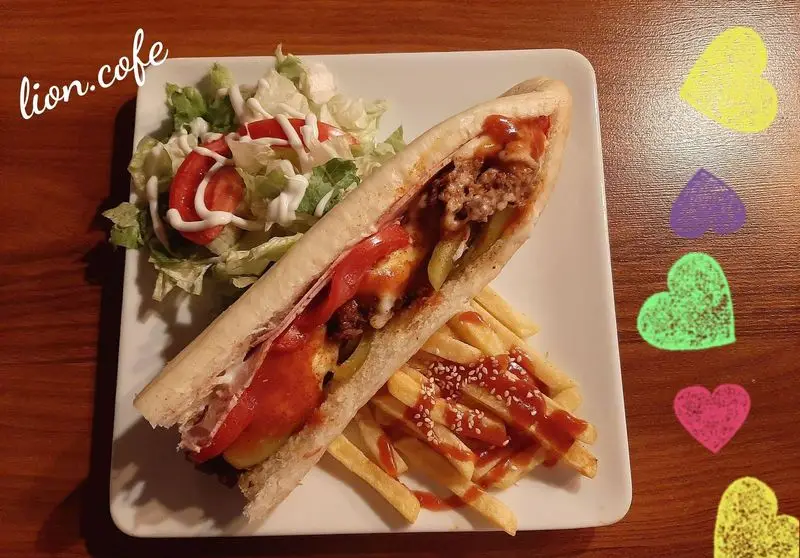 ساندویچ مخصوص و خوشمزه لیون کافه با مواد تازه، سیب زمینی سرخ کرده ترد و سالاد کنار غذا، تجربه‌ای لذت‌بخش از یک وعده غذایی کامل.