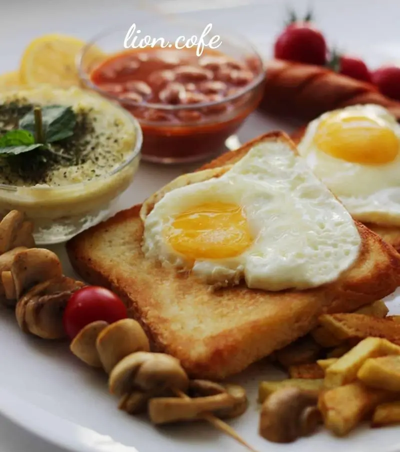 صبحانه انگلیسی خوشمزه از لیون کافه شامل تخم مرغ عسلی روی نان تست، لوبیا، قارچ، سیب زمینی سرخ کرده و حمص.