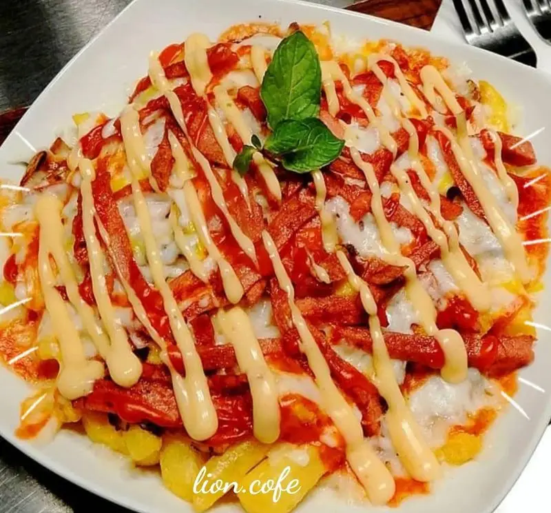 سیب زمینی سرخ شده پر شده با سوسیس، پنیر موزارلا ذوب شده، سس کچاپ و سس مایونز مخصوص همراه با برگ نعنا، یک پیش غذای عالی از لیون کافه.