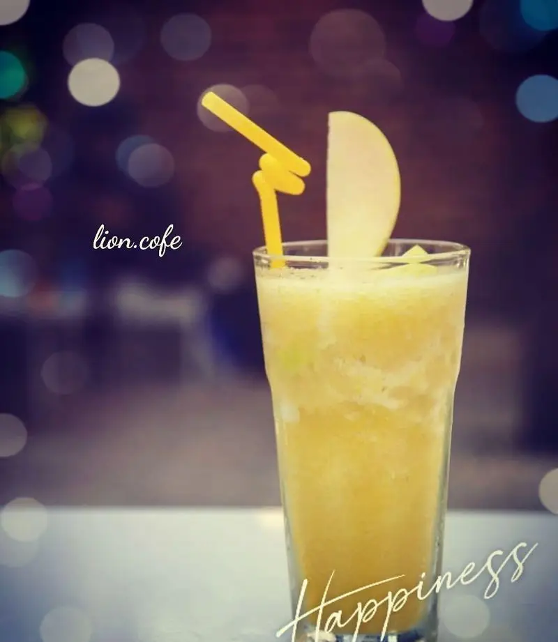 اسموتی میوه‌ای زرد رنگ خنک و دلپذیر "لیون کافه" با نی فانتزی و تزیین سیب تازه، انتخابی عالی برای شادابی در روزهای گرم.