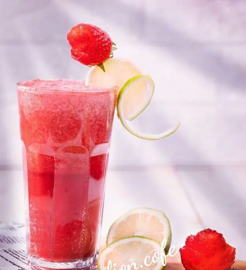 اسموتی توت فرنگی خنک و گوارا از لیون کافه، تزیین شده با توت فرنگی‌های تازه و برش‌های لیمو، انتخابی عالی برای روزهای گرم.