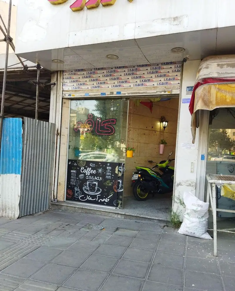نمای بیرونی کافه لیون، مکانی دنج برای قهوه، با ورودی شیشه ای، تابلوی "کافه آسمان" و کرکره KAVIRAL.