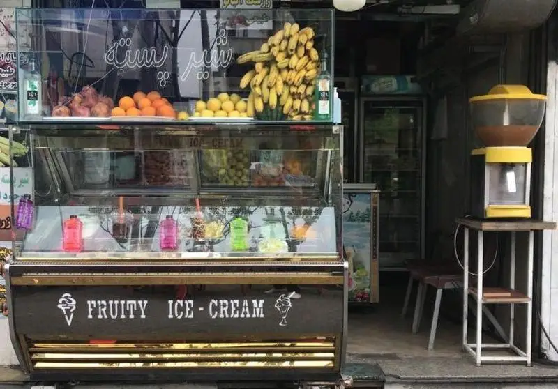 آبمیوه بستنی دلتا: ویترین مغازه با میوه‌های تازه، انواع بستنی فروتی و شربت، آماده سرو در یک روز گرم تابستانی.