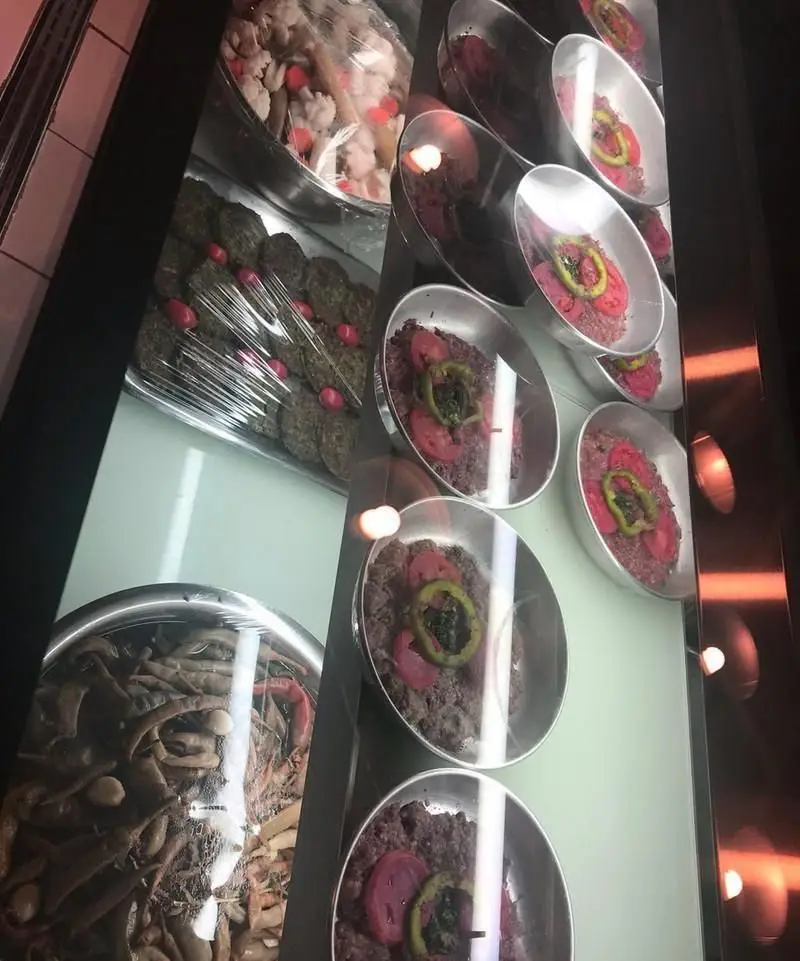 نمایش غذاهای لذیذ ایرانی در ویترین رستوران آقا خان، شامل کوفته، مایه کباب و انواع ترشی در سینی‌های آماده.