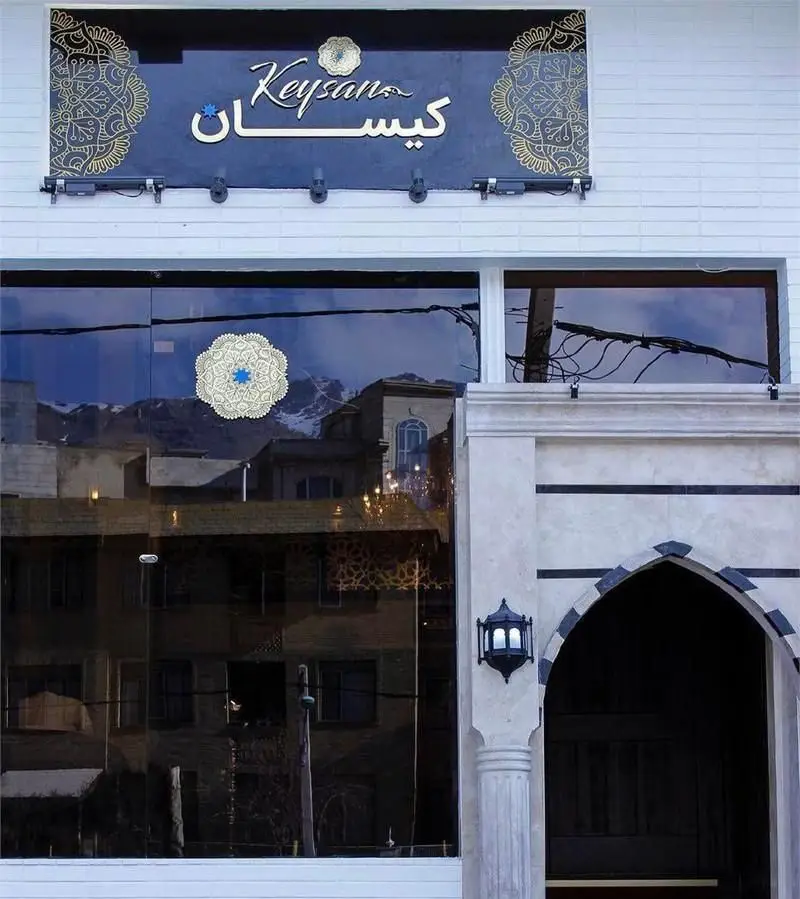 نمای بیرونی شیک کافی شاپ کیسان با تابلوی نام کسب و کار به فارسی و انگلیسی، دکوراسیون تلفیقی سنتی و مدرن و ورودی جذاب با قوس.