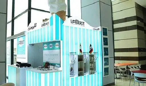 تصویر دکه روشن و جذاب بستنی ایتالیایی لابریت با خطوط آبی و سفید، همراه با مدل بزرگ یک قیف بستنی در بالای آن، واقع در یک فضای عمومی.