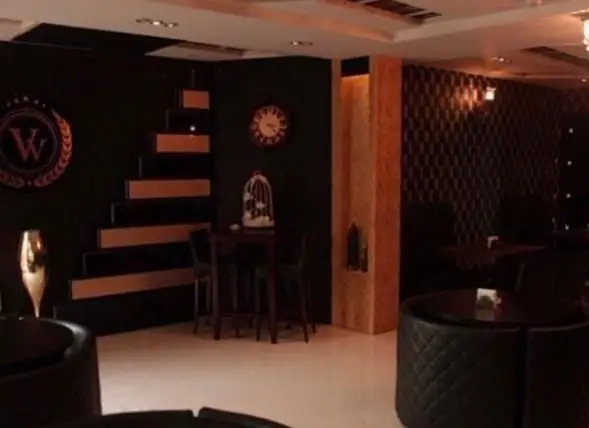 فضای داخلی کافه فرانسوی ویوات با دکوراسیون شیک، دیوار مشکی، پله‌های دکوراتیو طلایی و مبلمان مدرن، محیطی دنج برای مشتریان.