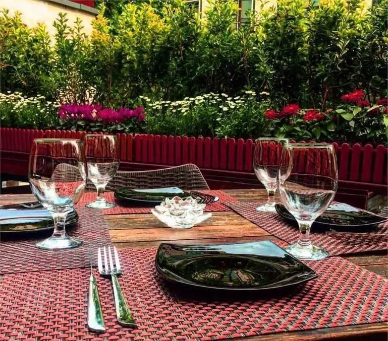 محیط زیبای فضای باز کافه فرانسوی ویوات با میز چیدمان شده، باغچه و گلهای رنگی، مناسب صرف غذا و لحظات دلنشین.