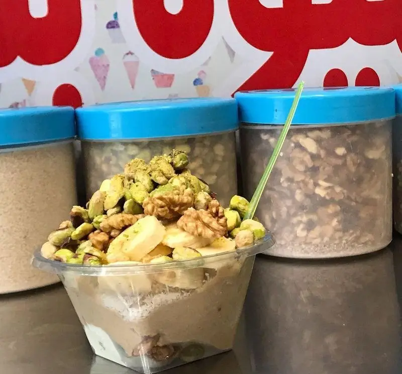 دسر مغز و موز جذاب از آبمیوه فردین با پسته و گردوی تازه، ایده‌آل برای یک میان وعده سالم و مقوی در آبمیوه فروشی.