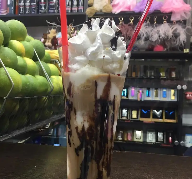 نوشیدنی فراپه قهوه سرد و خوشمزه ابمیوه فردین با خامه و سس شکلات، در کنار میوه های تازه و چیدمان جذاب فروشگاه.